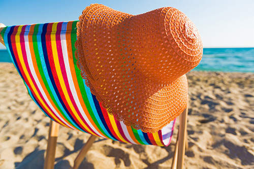 Sdraio colorata con cappello appoggiato sopra in spiaggia  in una giornata di sole